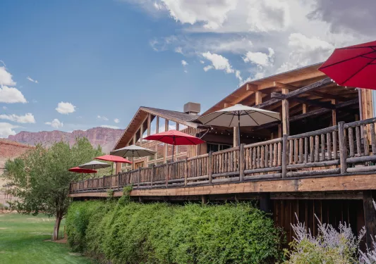 Elevated cabin-style building with wooden railings, in front of a grass valley