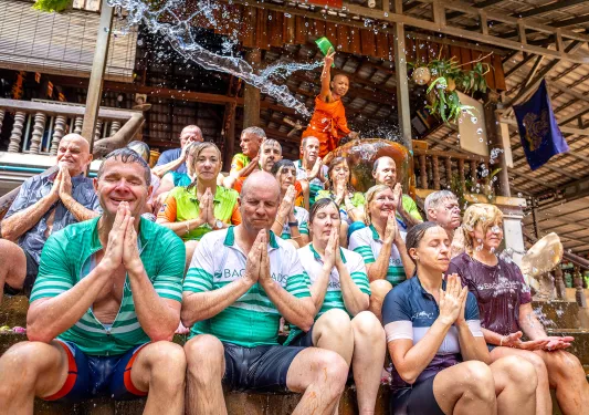 a group of people get splashed with water in a ceremony outside a temple