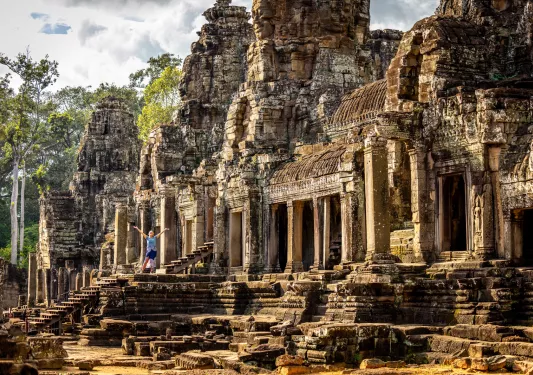 Woman with arms open next to ancient temple ruins