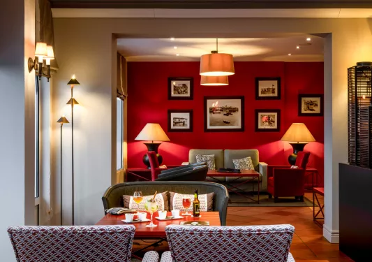 Lounge and dining area with a red wall with paitnings hanging