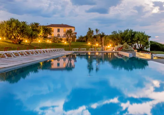Outdoor pool with illuminated lights and large trees surrounding