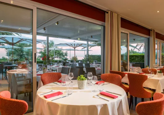 Indoor dining hall with circular tables, white cloths and red chairs