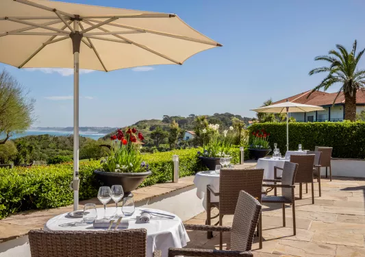 Outdoor dining patio with large umbrellas, looking out to a large valley