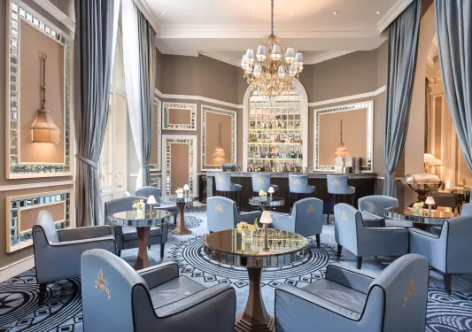 Indoor bar with blue, cushioned seats around glass tables