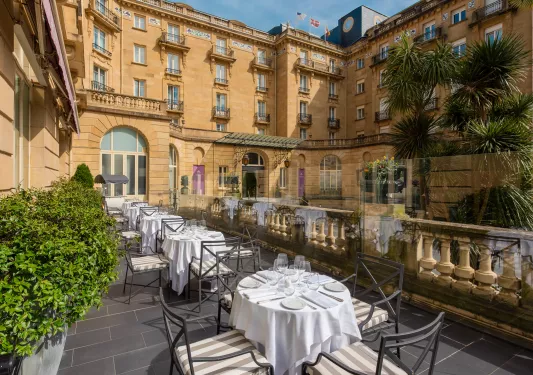 Outdoor balcony with dining tables and metal chairs