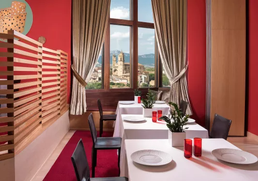 Indoor dining area with tables cover with a white cloth, and wine glasses on each table