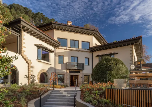 Exterior view of tan colored hotel building with a circular staircase in front