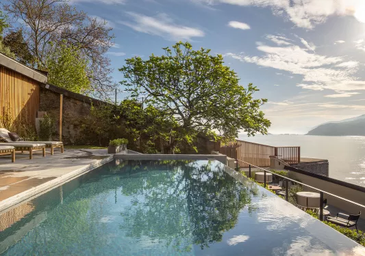 Outdoor infinity pool overlooking a lake to the right