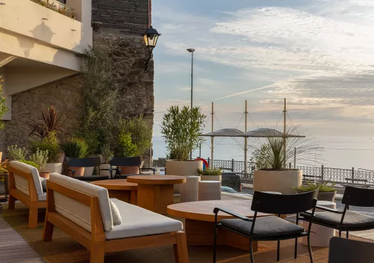 Outdoor patio and lounge area with cushioned seats, overlooking a lake to the right