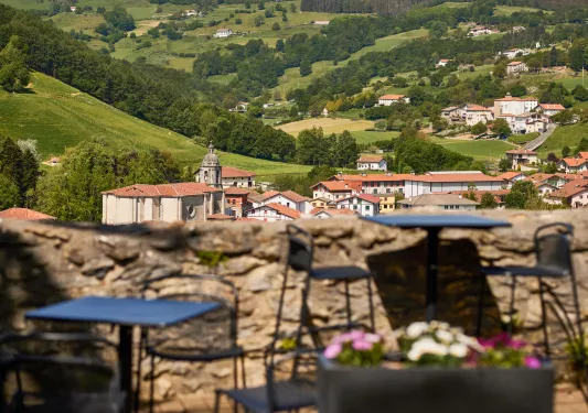 Stone barricade with tables and chairs, with a rustic town in the distance