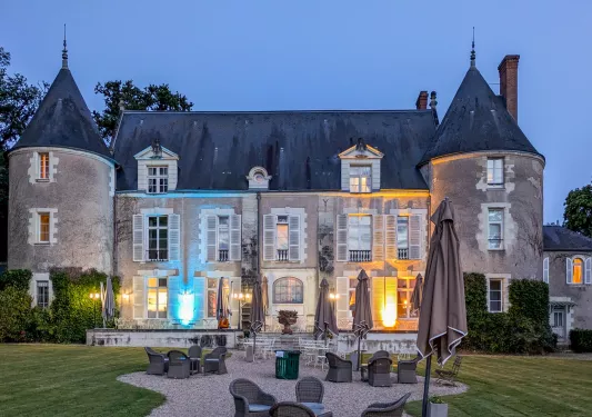 Exterior view of stone, castle-like building with blue and orange lights with a grass area in front