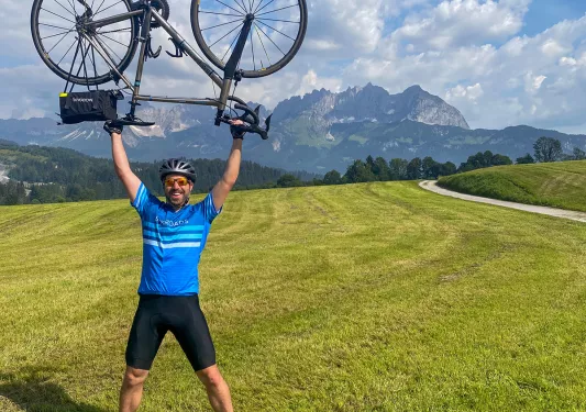Man in a grassy field holding up a bike over his head