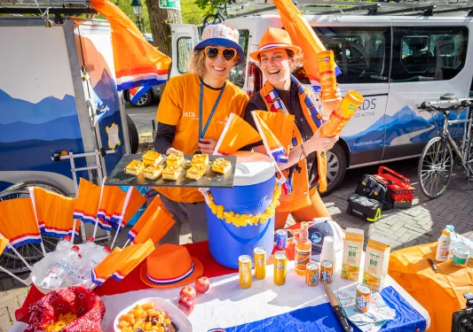 Man and women in orange clothing holding up pastries