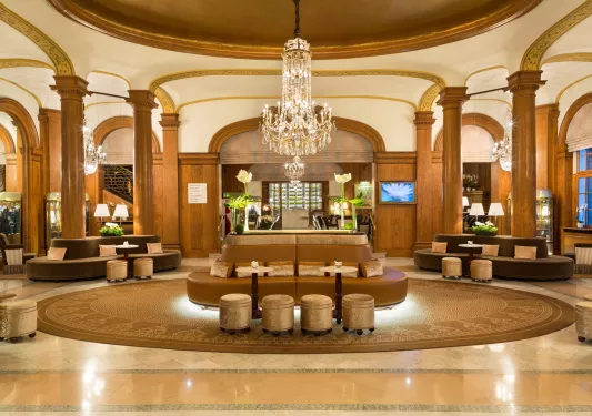 Indoor lobby with brown and tan leather sofas and a large chandelier in the center