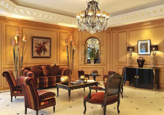 Indoor hotel lobby area with red-striped cushioned chairs and a chandelier