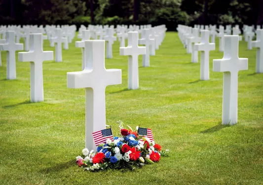 Memorial cemetery with white crosses on the ground, and a bouquet of flowers over the grass