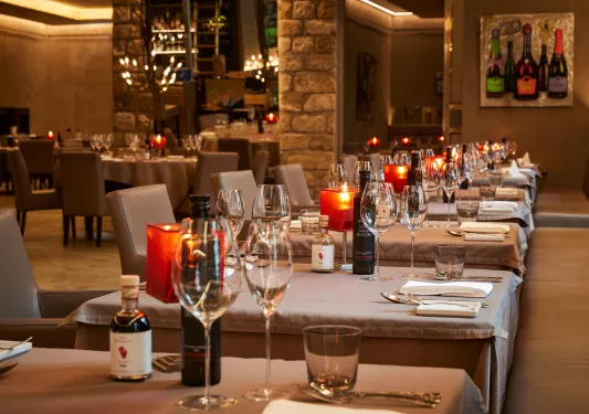Indoor dining area with gray tablecloths and glasses of wine on each table