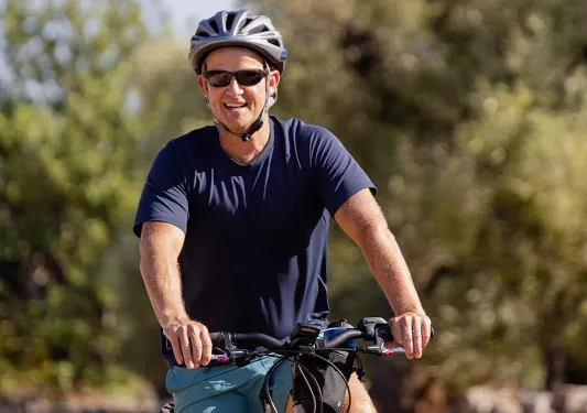 Man riding electric bike in front of a vineyard