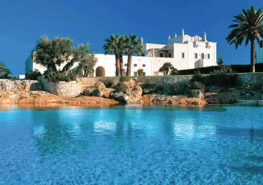 white building with palm trees next to ocean