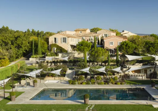 Outdoor hotel property view with an outdoor pool, surrounded by trees