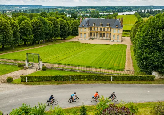 cyclists ride by manicured lawns