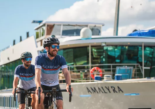 cyclist riding by boats on river