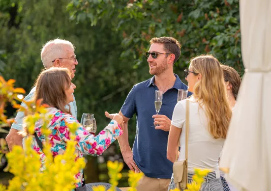 Group of men and women drinking from glasses of wine while they're talking