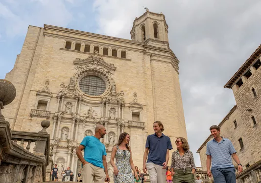 Group of men and women walking down a large flight of stairs in front of a rustic stone building