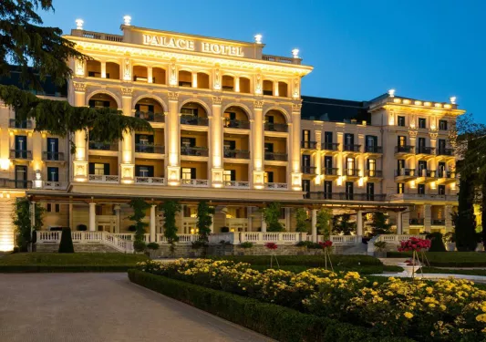 Large hotel building with columns and gardens out front