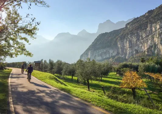 Two bikers on a road through grassy fields