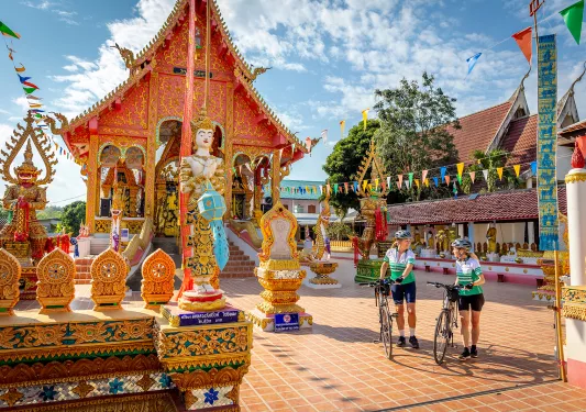 Two woman with bikes walking through a decorated town square