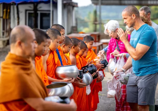 Group of people praying in front of monks with orange robes