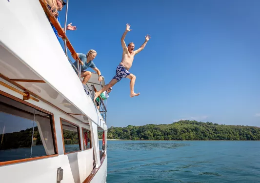 Man jumping off boat into water