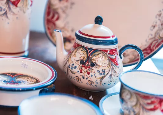 red, white and blue teapot with cups surrounding