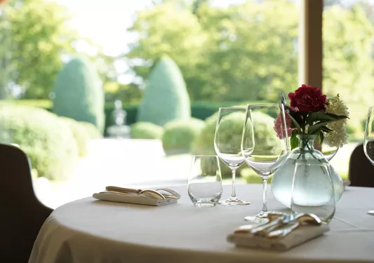 Dining table with a vase with flowers in the center, and 3 empty glasses of wine