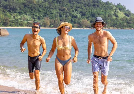 Three people running on the beach