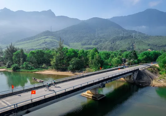 Bike riders cross a large bridge