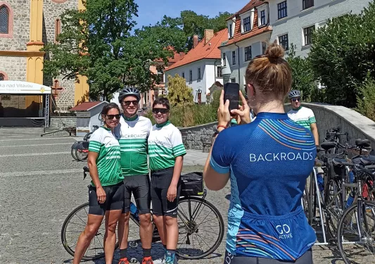 Woman taking a photo of three people in the middle od a town center
