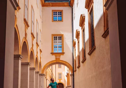 Man standing in an alleyway between two, rustic stone buildings
