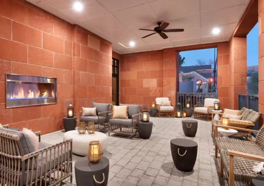 Indoor lobby with red stone walls, woven chairs and a fireplace in the wall