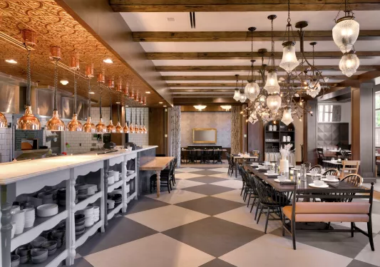 Dining hall with large light fixtures and a counter on the left full of black and white plates
