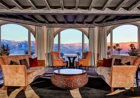 Indoor lounge and seating area, with tan velvet sofas and large windows