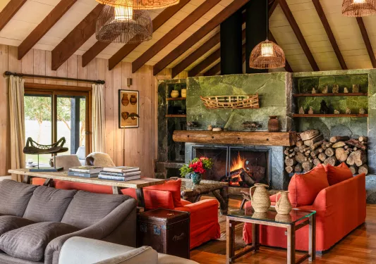 Indoor cabin lobby with red sofas in front of a green stone fireplace