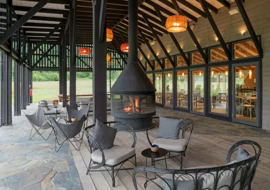 Outdoor seating area with a large, black fire pit, with black metal chairs surrounding it