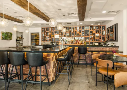 Indoor bar and lounge with black stools and cushioned, leather chairs