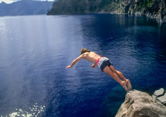Man jumping of a cliff into a lake
