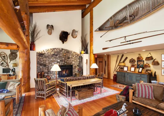 Indoor lobby with wooden pillars, a stone fireplace and animal heads on the wall
