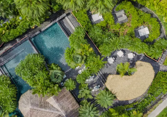 Top view of outdoor pool with straw hut coverings on the right of the pool