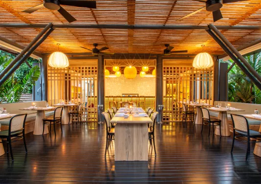Indoor dining hall with tall black chairs and wooden dining tables, surrounded by orange lights
