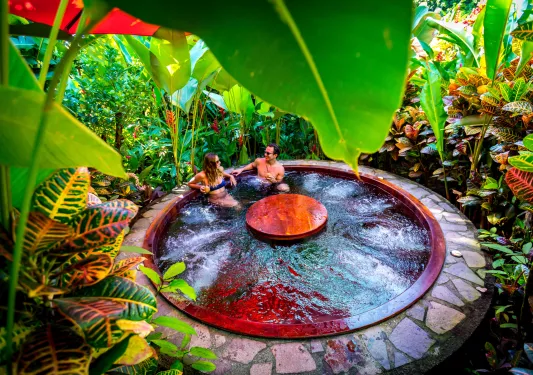 Man and woman in a red hot tub with a table in the center